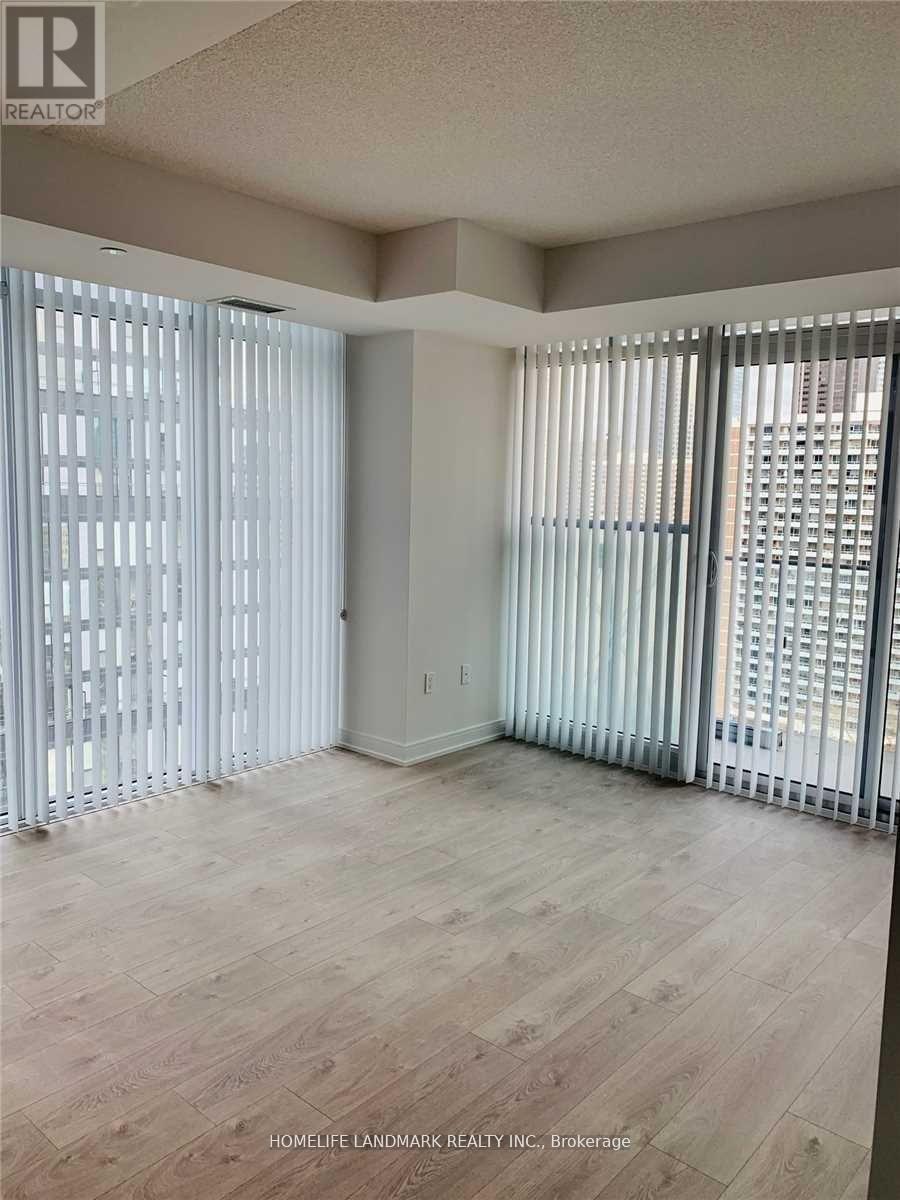 A room with wooden flooring and white vertical blinds on the windows.