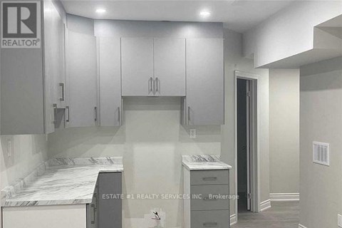 A kitchen with white cabinets and a marble countertop.
