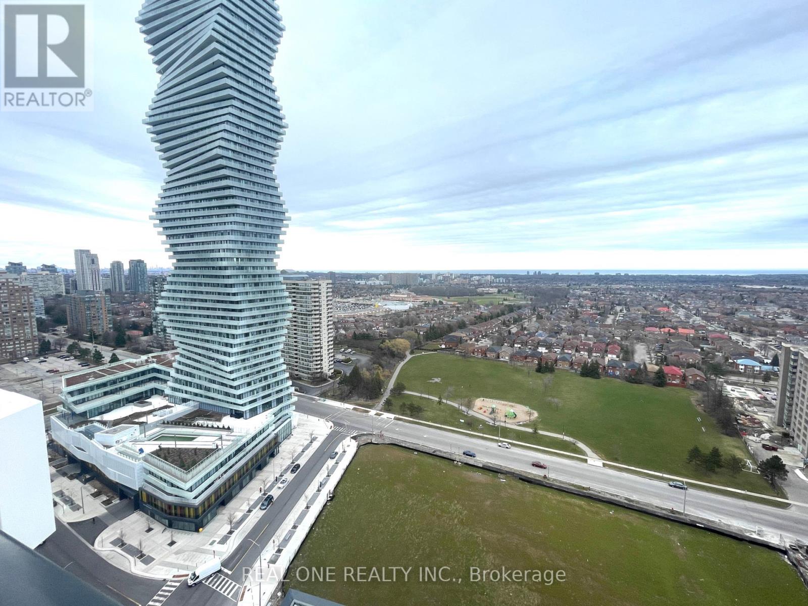 A tall, slender building with a unique design stands out in a cityscape.