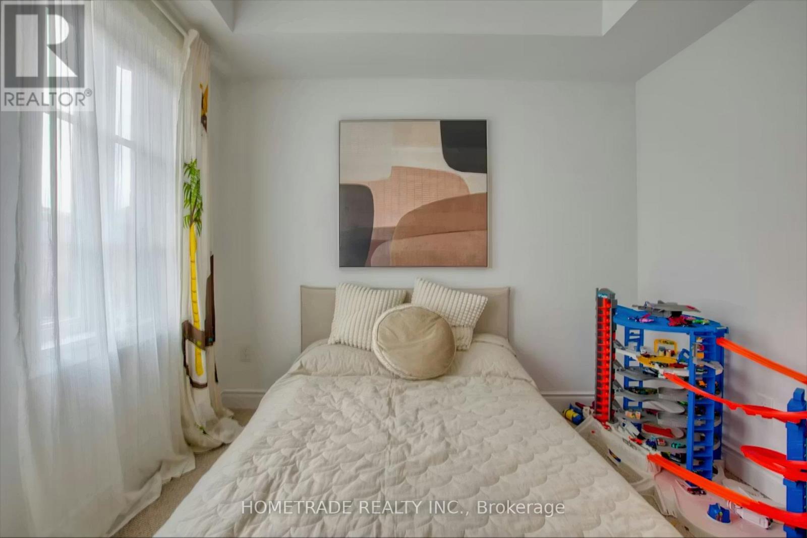 A bedroom with a white bed and a painting on the wall.