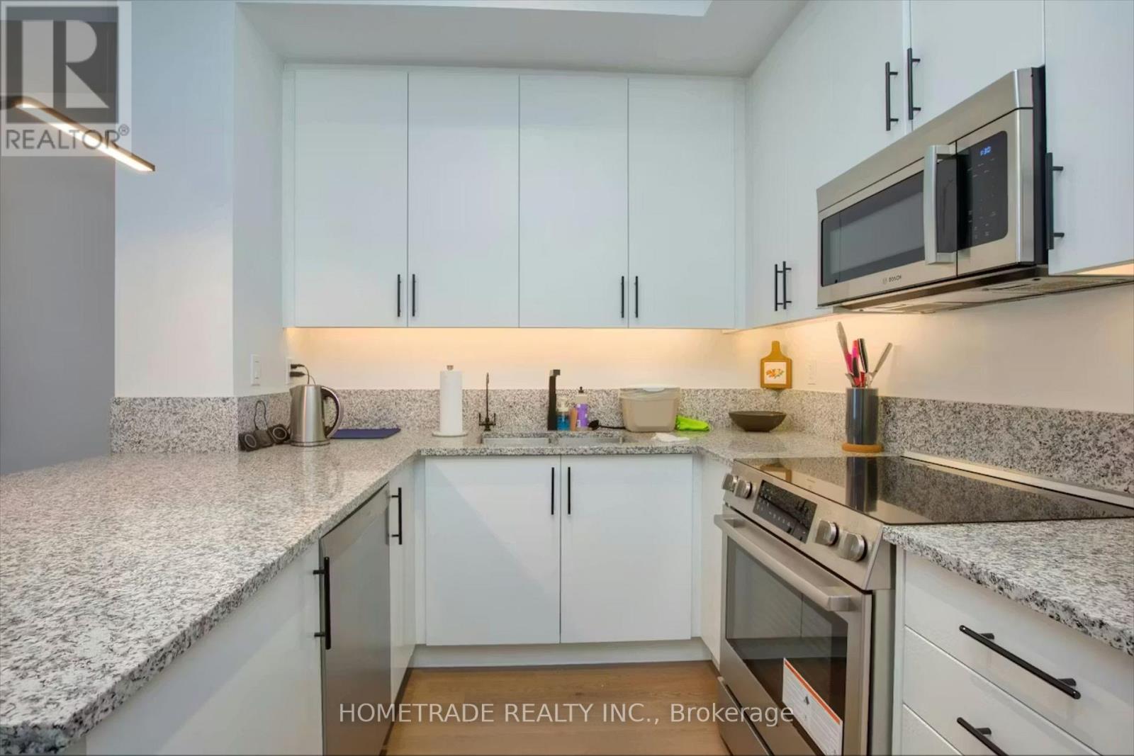A modern kitchen with white cabinets and granite countertops.