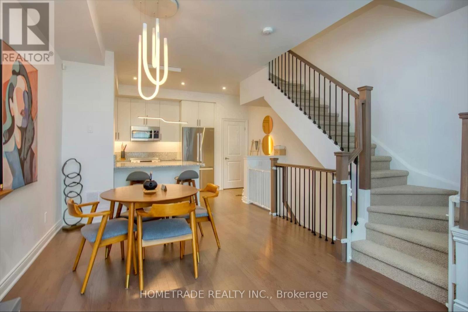A well-lit, spacious interior of a home with a dining area and staircase.