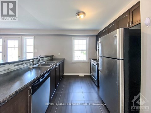 A kitchen with a black refrigerator and a sink.