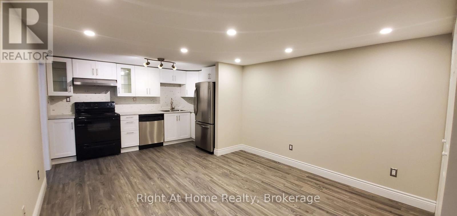 A kitchen with a black fridge and stove top oven.