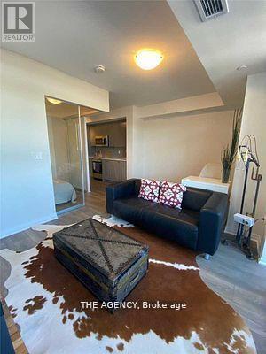 A living room with a black couch and a cowhide rug.
