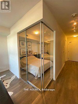 A bedroom with a bed and a mirrored wardrobe.