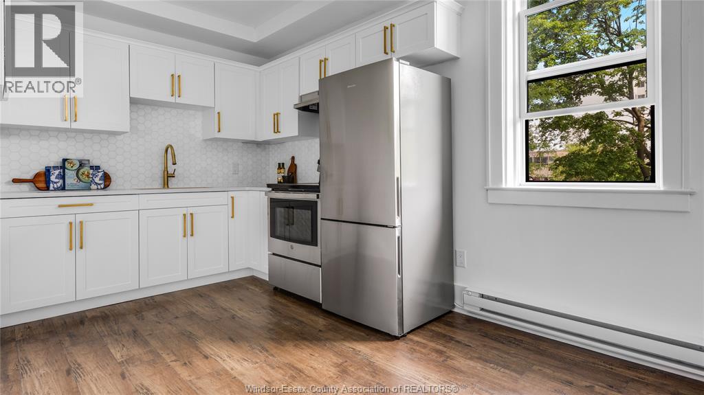 A kitchen with white cabinets and a stainless steel refrigerator.