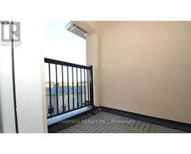 A balcony with a black railing and a view of buildings outside.