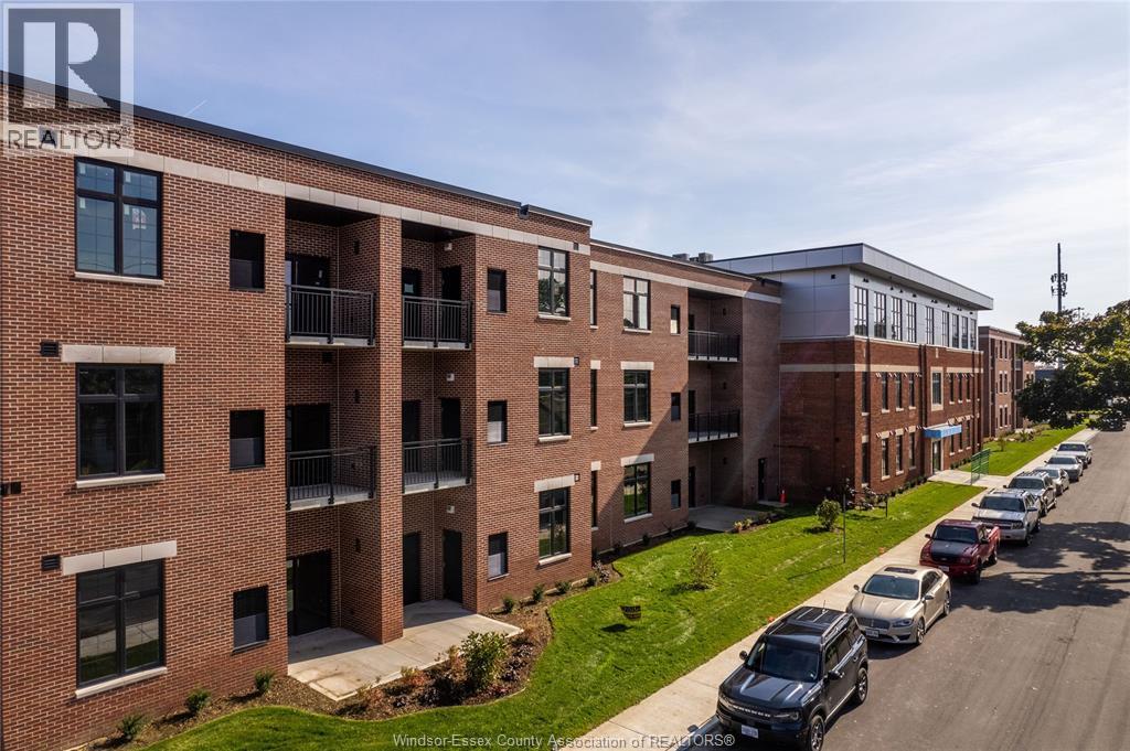 A row of red brick apartment buildings with cars parked in front.