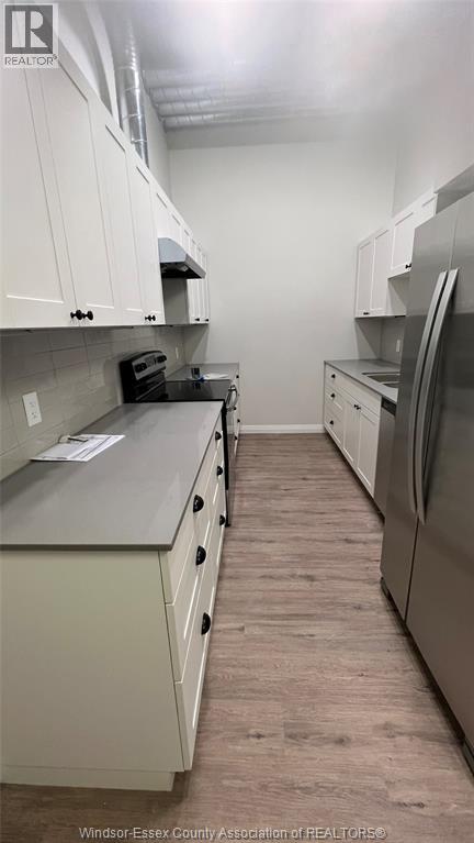 A kitchen with white cabinets and a wooden floor.