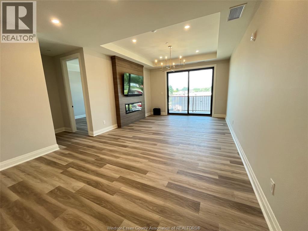 A spacious room with wooden flooring and a large window.