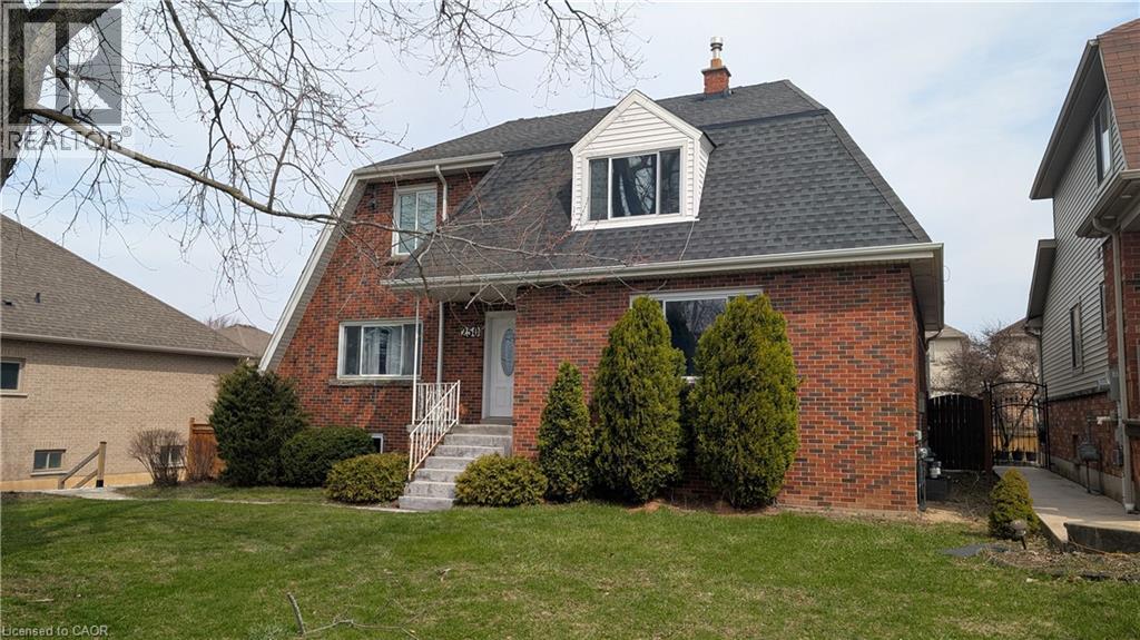A red brick house with a white window and a black roof.