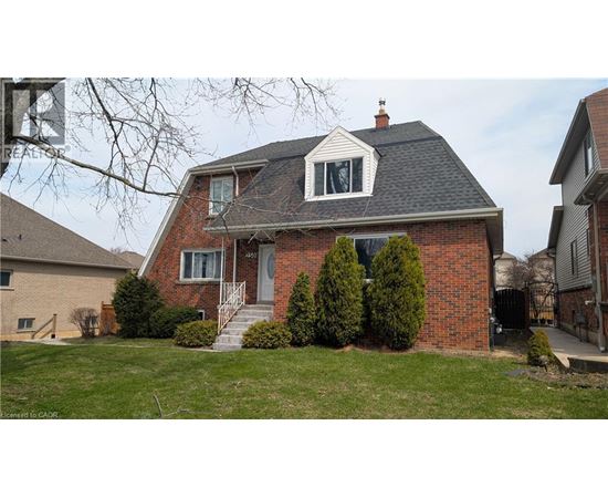 A red brick house with a white window and a black roof.