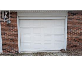 A white garage door is closed and has a sign above it that says "REALTOR".