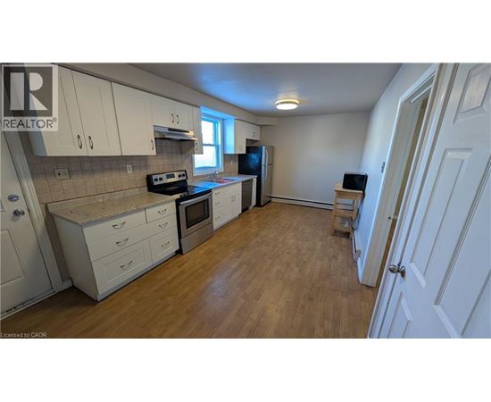 A kitchen with white cabinets and wooden floors.