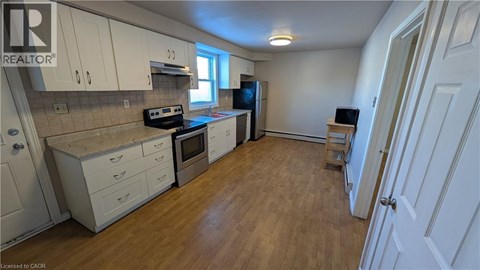A kitchen with white cabinets and wooden floors.