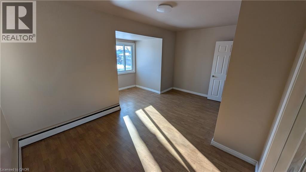 A spacious room with wooden flooring and a window letting in natural light.