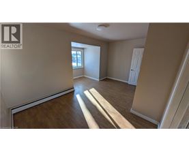 A spacious room with wooden flooring and a window letting in natural light.