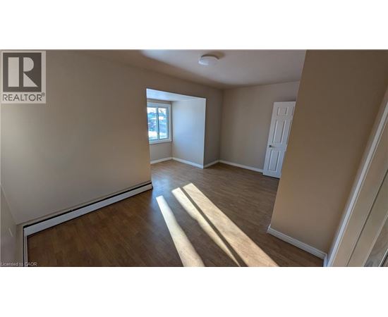A spacious room with wooden flooring and a window letting in natural light.
