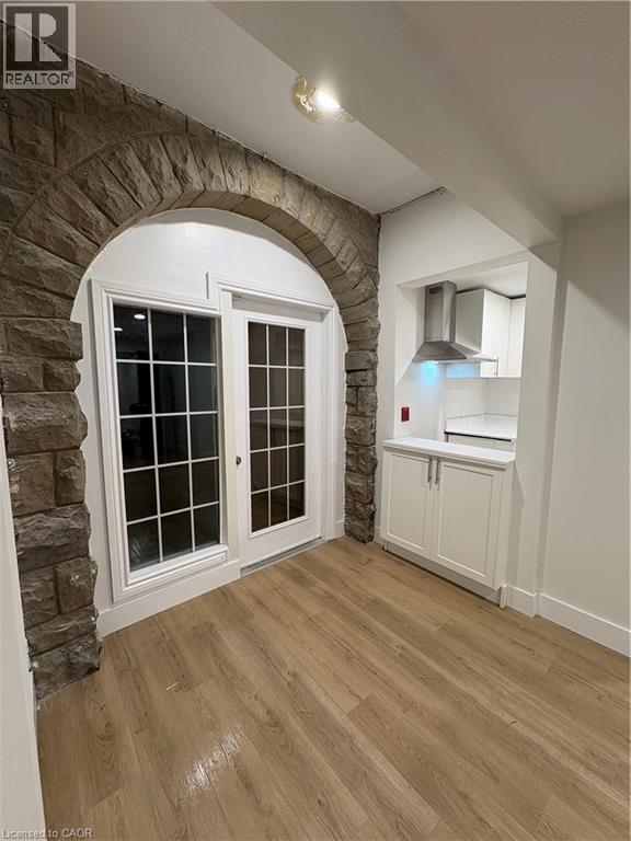 A kitchen area with a stone archway and wooden flooring.