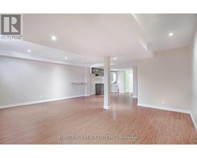 A spacious room with wooden flooring and white walls, part of a real estate listing.