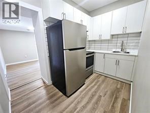 A kitchen with a stainless steel refrigerator and wooden floors.