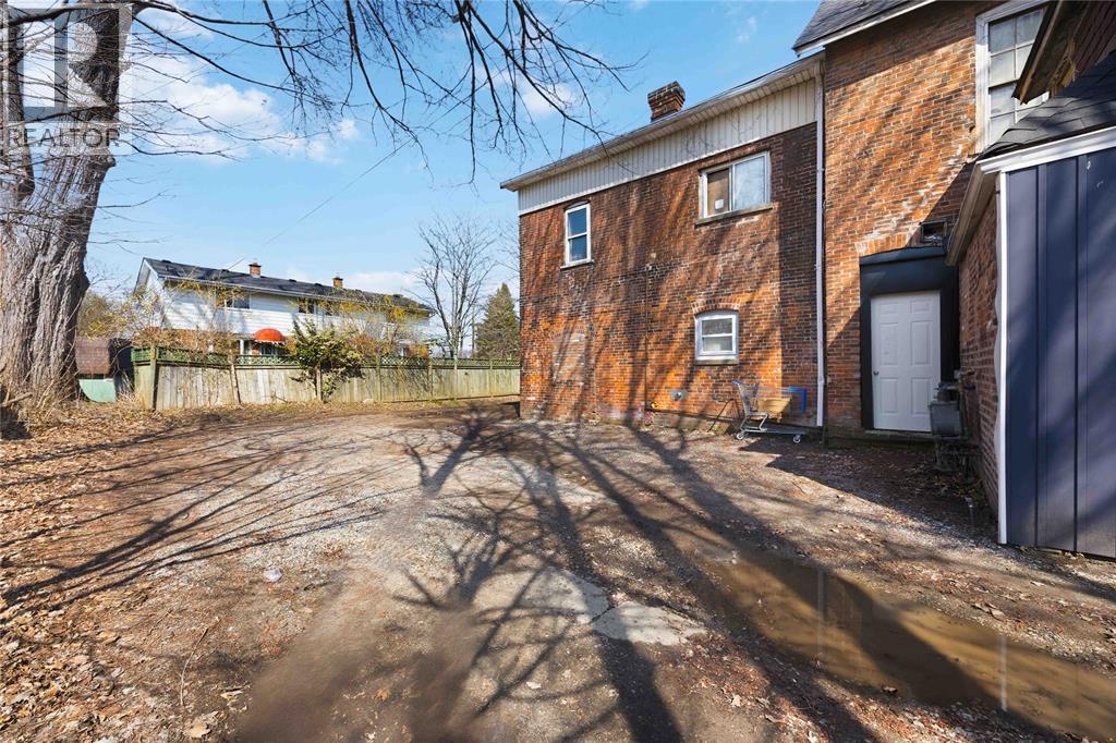 A dirt path leads to a brick building with a white door.
