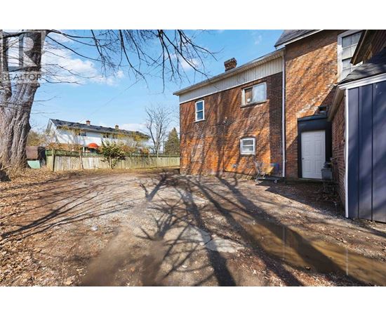 A dirt path leads to a brick building with a white door.