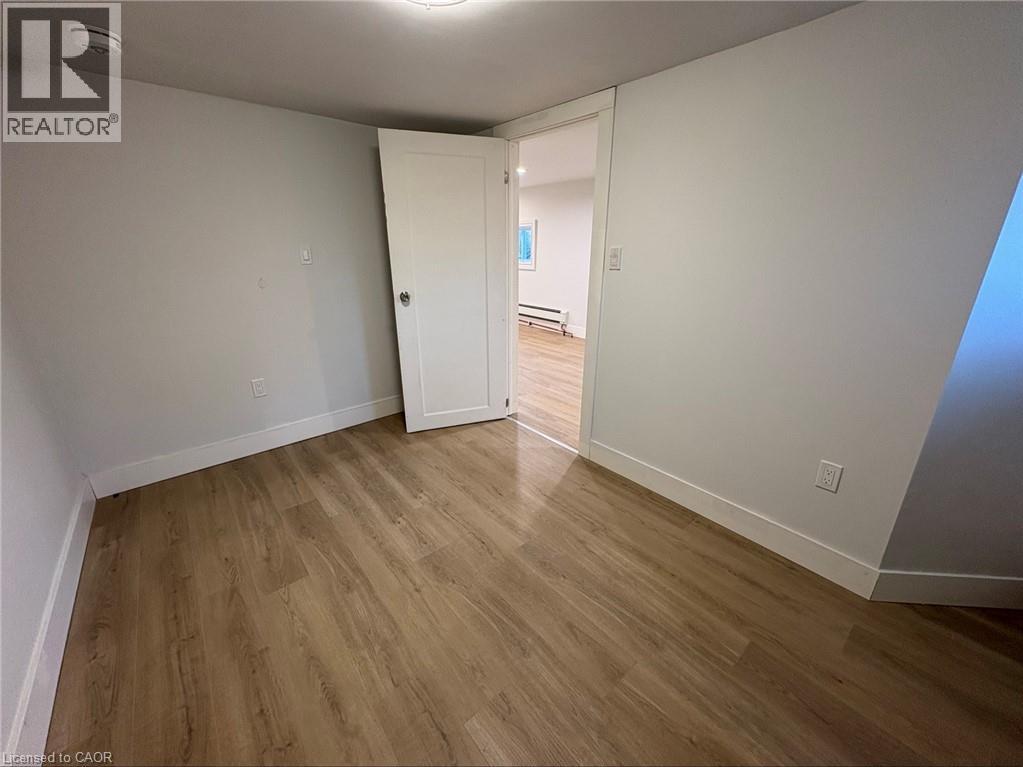 A room with wooden flooring and white walls, with a doorway leading to another room.