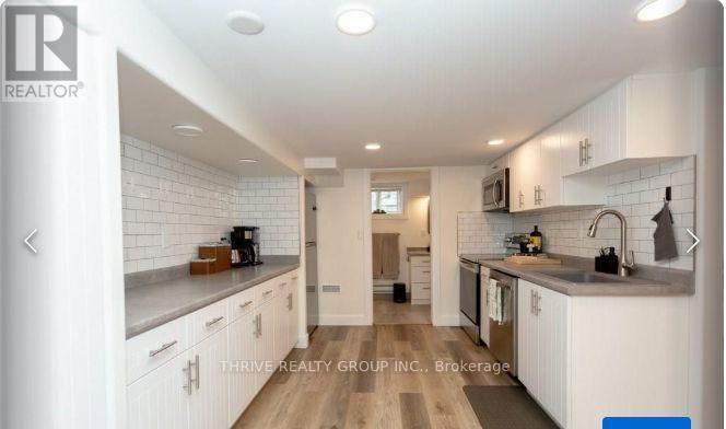 A modern kitchen with white cabinets and a wooden floor.