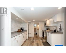 A modern kitchen with white cabinets and a wooden floor.
