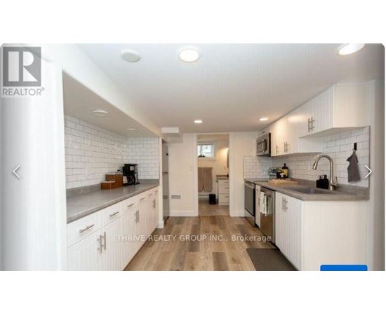 A modern kitchen with white cabinets and a wooden floor.
