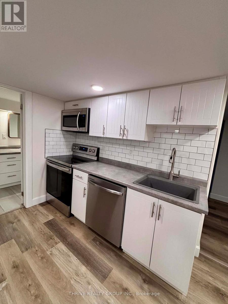 A kitchen with white cabinets and a wooden floor.