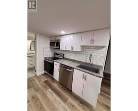 A kitchen with white cabinets and a wooden floor.
