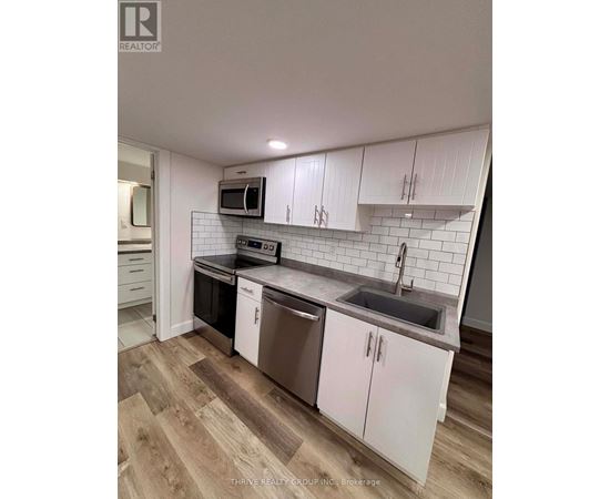 A kitchen with white cabinets and a wooden floor.