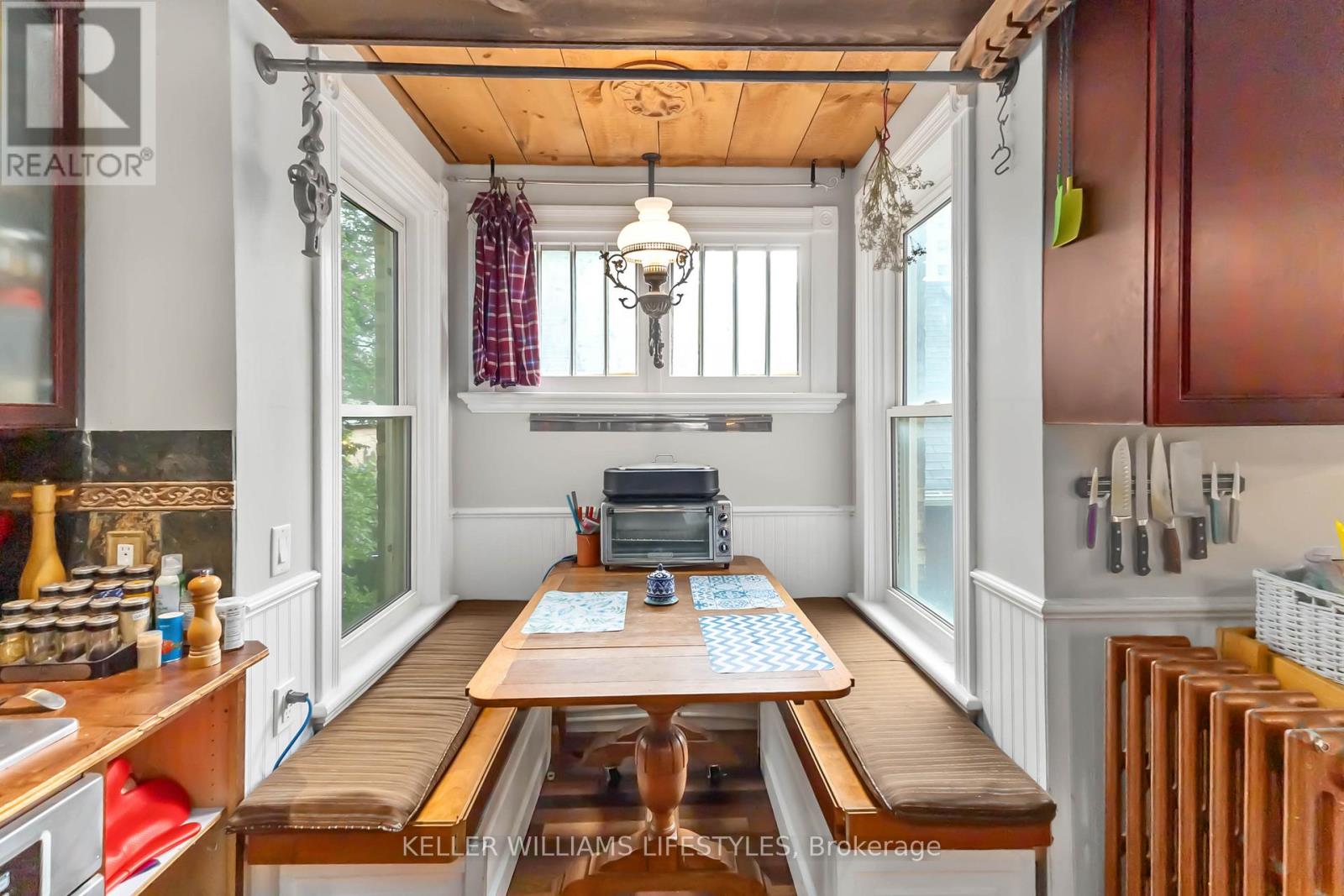 A kitchen with a wooden table and a chandelier hanging from the ceiling.