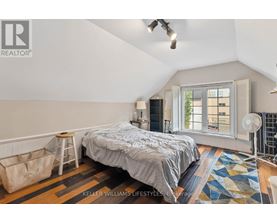 A bedroom with a bed, a window with blinds, and a rug on the floor.