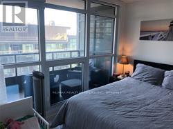 A bedroom with a large bed and a window overlooking a cityscape.