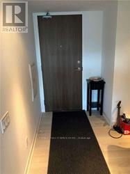 A hallway with a black carpet and a wooden door.