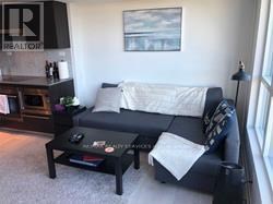 A black couch with a white pillow and a black coffee table in a living room.