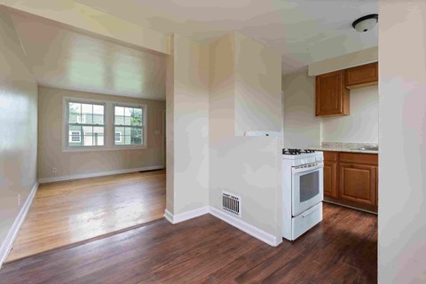 A kitchen with a white stove top oven and wooden cabinets.