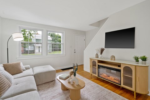 A living room with a white couch, a coffee table, and a fireplace.