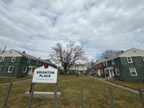 A sign that says Brighton Place stands in front of a row of townhouses.