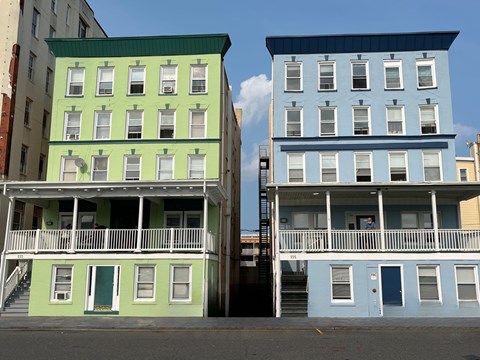 Two buildings with green and blue facades stand side by side.