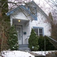 A white house with a blue trim and a small porch.