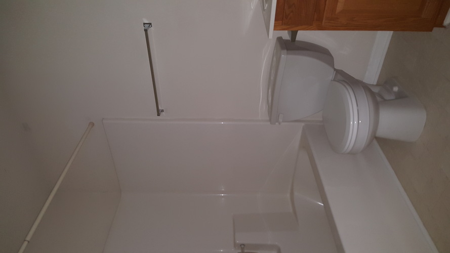 A white toilet with a white tank and a white shower stall.