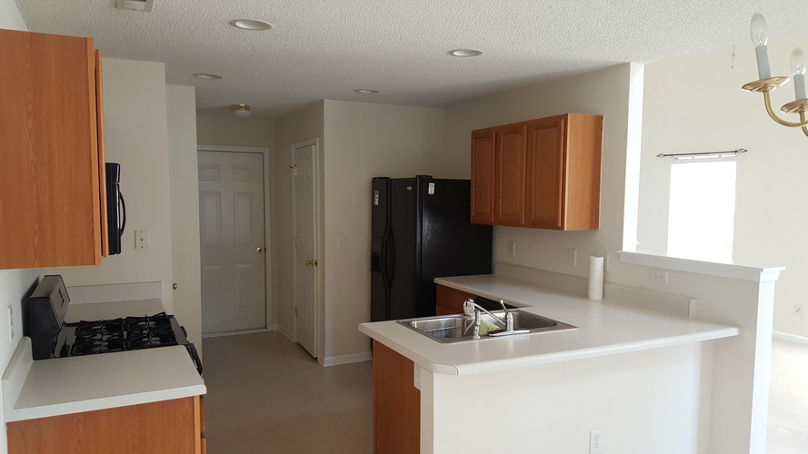 A kitchen with wooden cabinets and a black refrigerator.