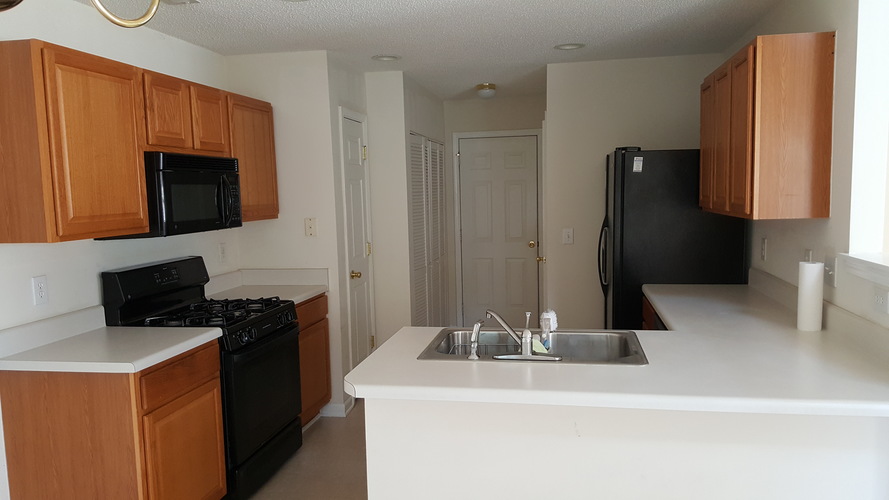 A kitchen with black appliances and wooden cabinets.
