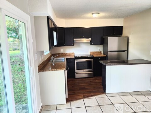 A kitchen with black cabinets and white appliances.
