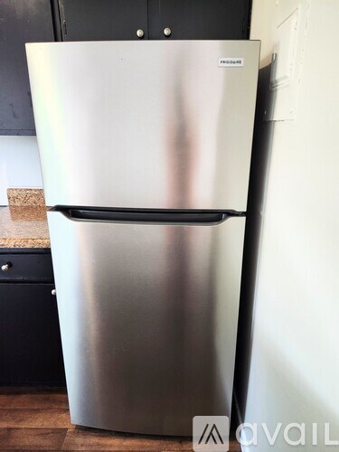 A silver fridge with a black handle is in a kitchen.